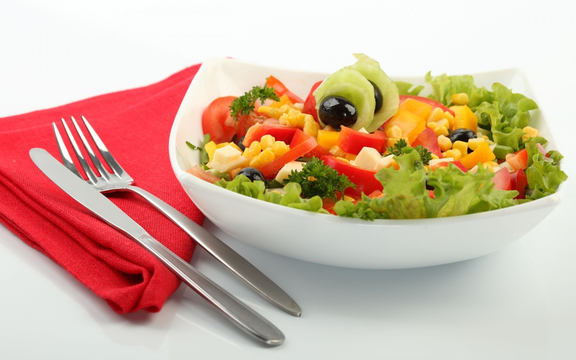 HD PC desktop wallpaper featuring a colorful fresh salad with lettuce, tomatoes, corn, olives, and peppers, accompanied by a fork and knife on a red napkin.