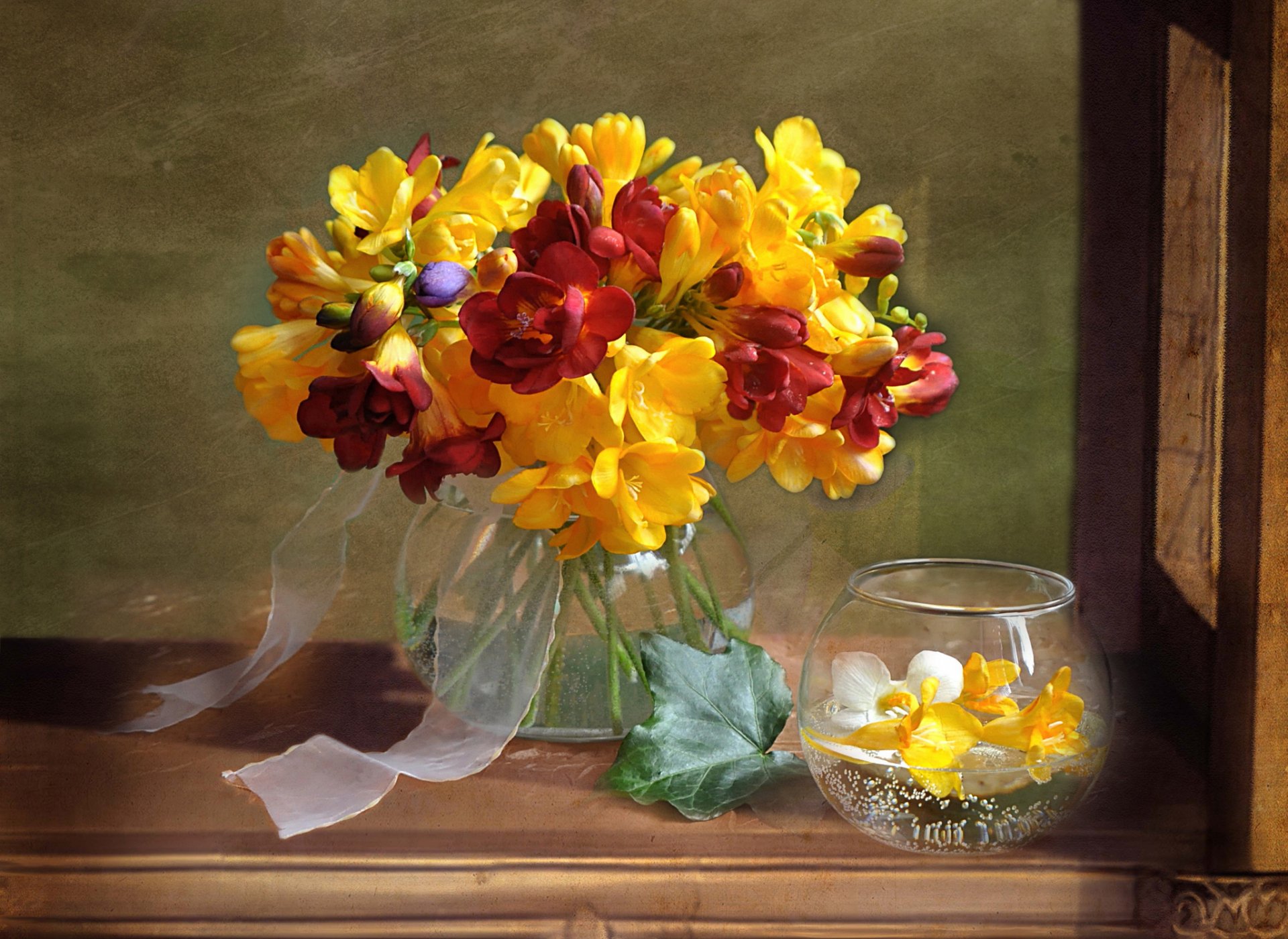 A vibrant arrangement of yellow and red flowers in a glass vase, accompanied by a smaller bowl of floral accents, set against a warm background. This HD wallpaper adds a cheerful touch to any desktop.
