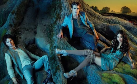 HD desktop wallpaper from The Vampire Diaries featuring three main characters posed dramatically against a large tree, enveloped in a mystical, atmospheric setting.