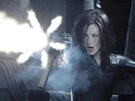 HD PC desktop wallpaper featuring a dramatic scene from the movie Underworld: Evolution, depicting a fierce woman firing a gun amidst smoke and dark surroundings.
