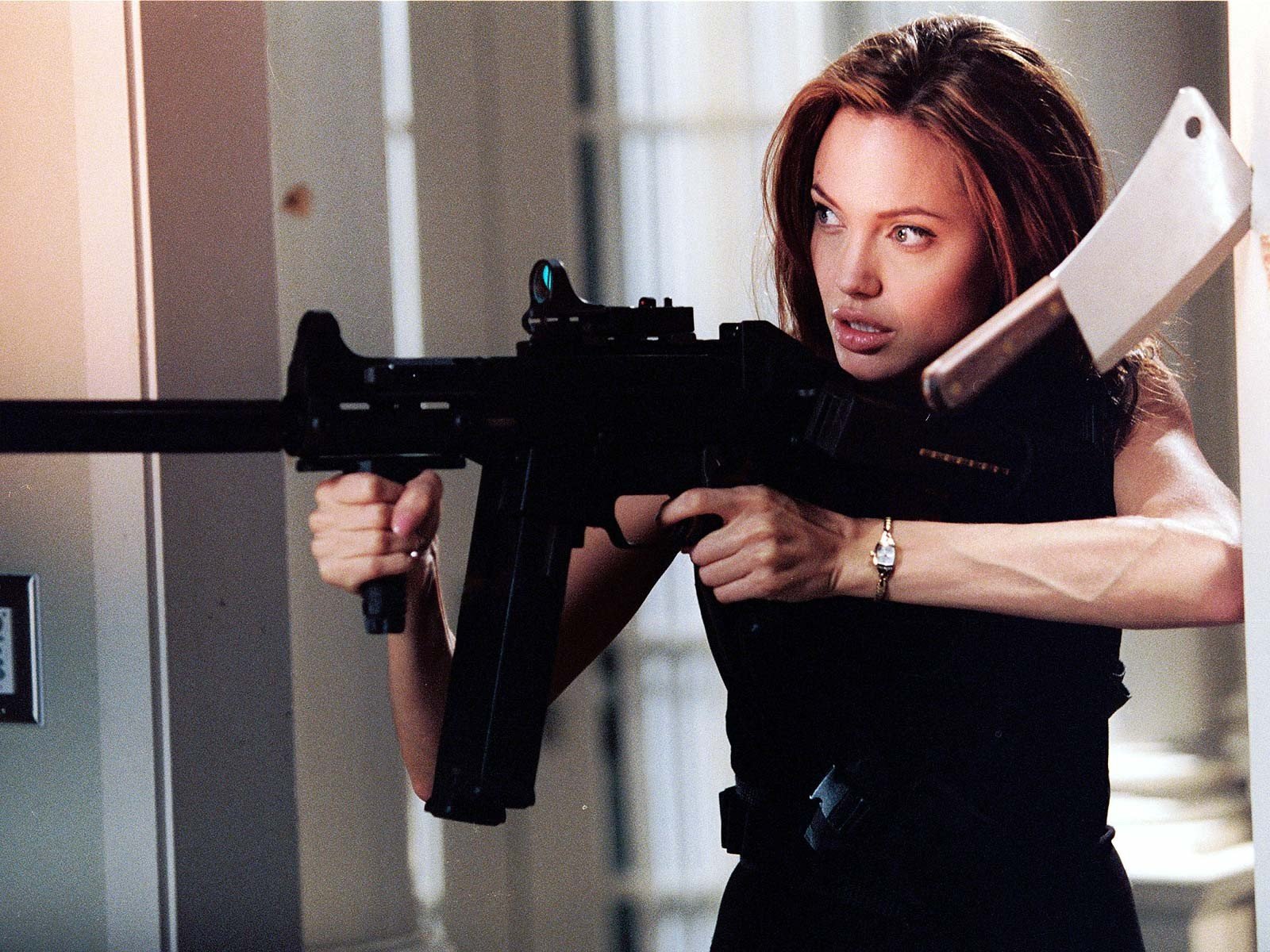 Angelina Jolie in a dynamic pose with a firearm, showcasing her role in the movie *Mr. & Mrs. Smith*. This HD wallpaper captures an intense moment from the film.