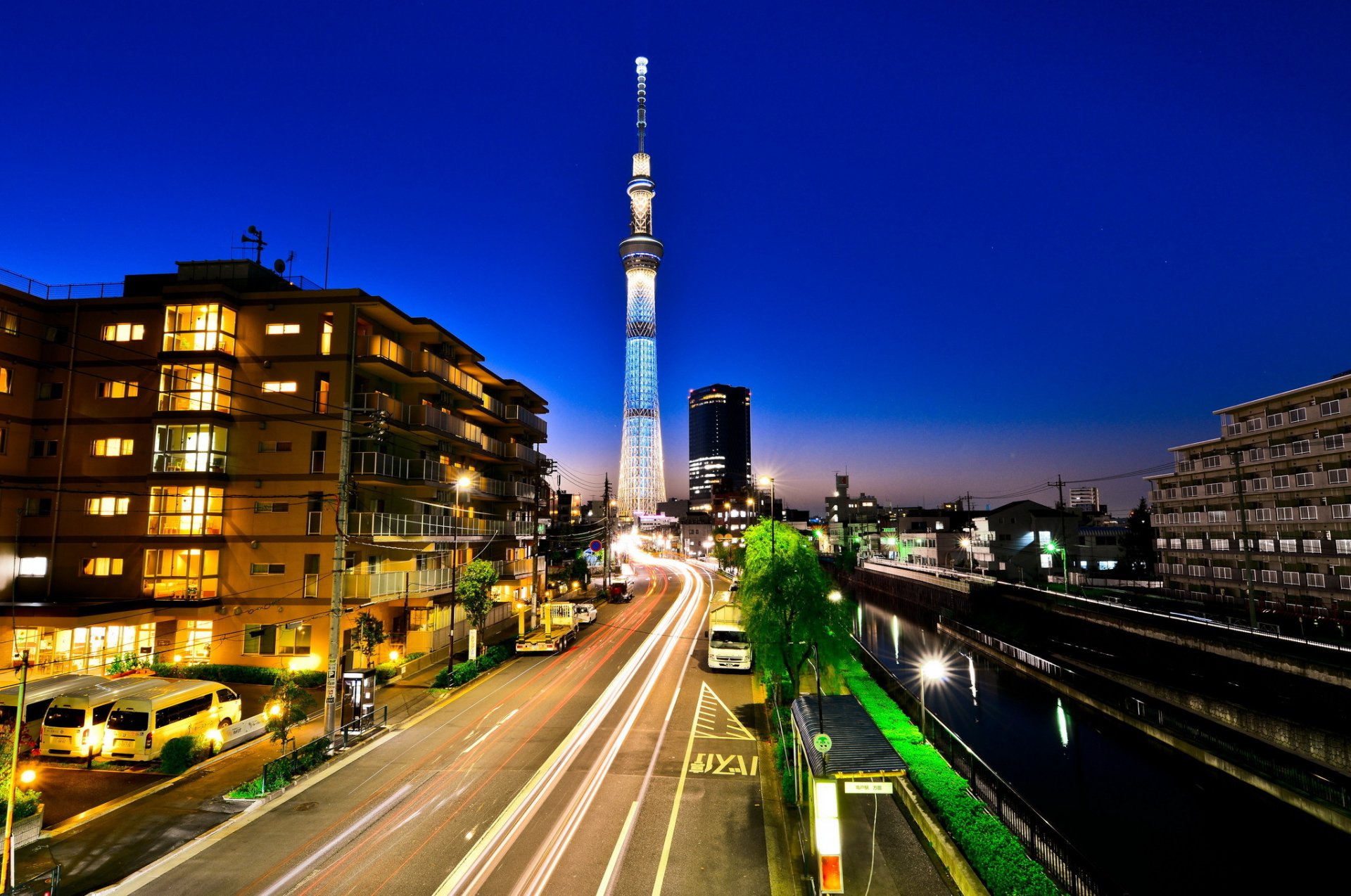 Time-lapse photography of a city street at night with light trails, featuring a prominent tower, captured in HD for a PC desktop wallpaper and background.