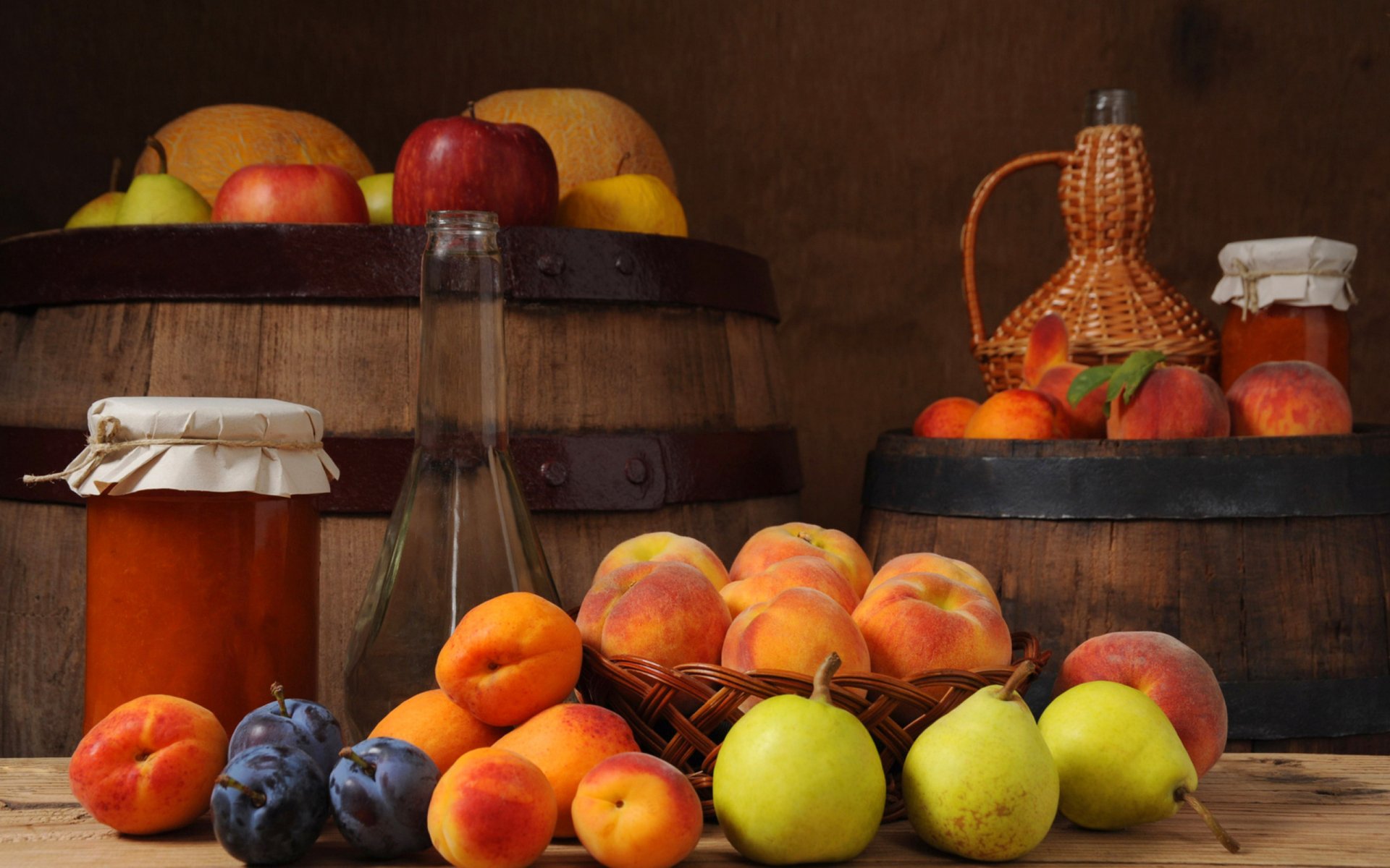 HD PC desktop wallpaper featuring an arrangement of fresh fruit and jars, set against rustic wooden barrels and a warm, earthy background.