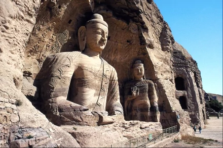 HD PC desktop wallpaper showcasing the intricately carved religious statues at Yungang Grottoes against a clear blue sky.