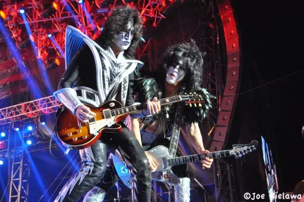 4K Ultra HD PC desktop wallpaper: two glam-rock guitarists in black-and-white face paint and elaborate costumes, playing electric guitars under red and blue stage lights.