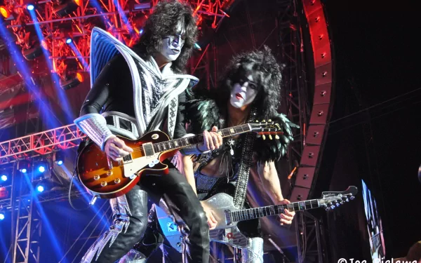 4K Ultra HD PC desktop wallpaper: two glam-rock guitarists in black-and-white face paint and elaborate costumes, playing electric guitars under red and blue stage lights.