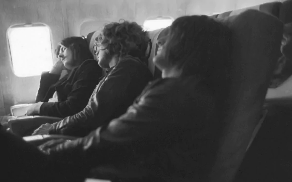 Black and white HD PC desktop wallpaper featuring members of Led Zeppelin resting on an airplane, capturing a candid moment of the iconic music band.