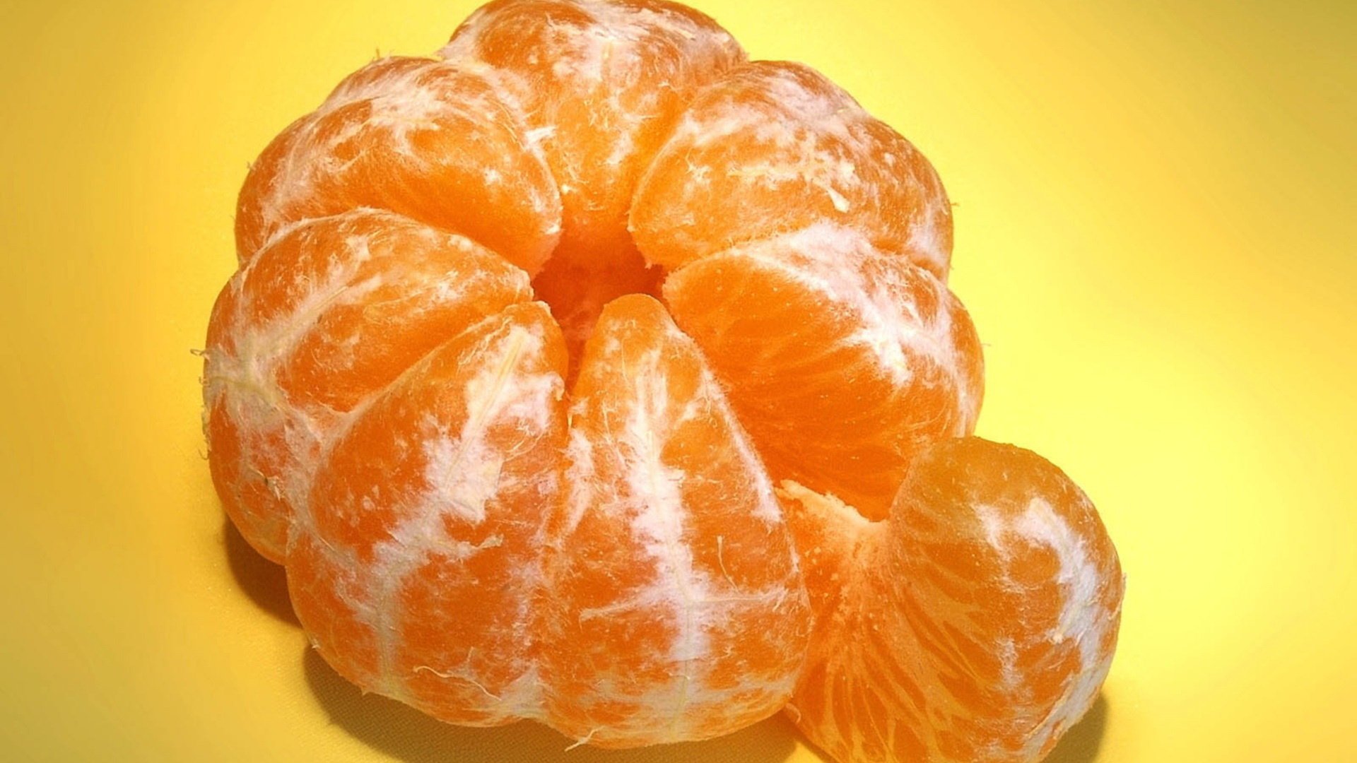 HD PC desktop wallpaper featuring a close-up of a peeled mandarin with vibrant orange segments against a bright yellow background.