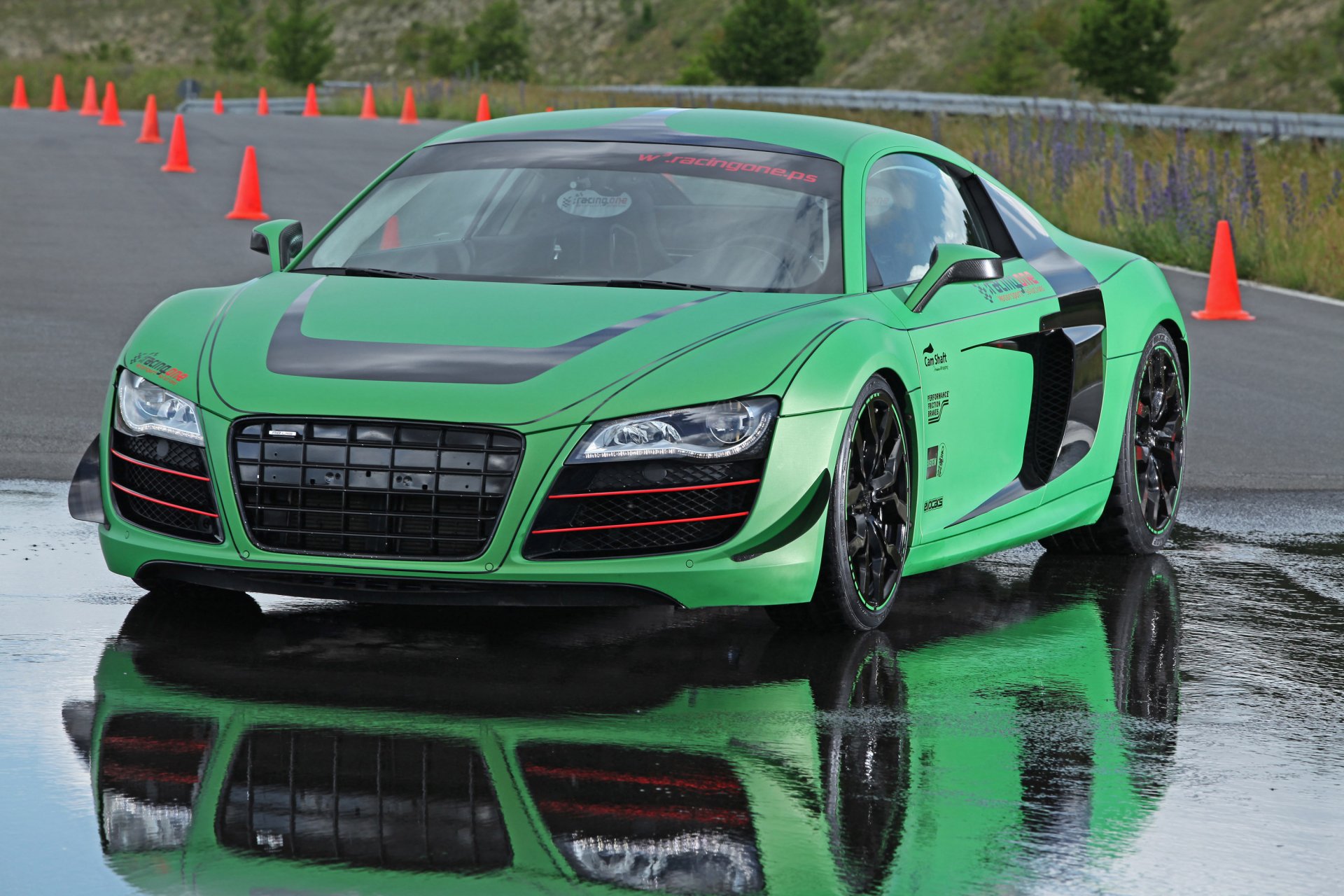 HD desktop wallpaper of a green Audi R8 sports car on a wet track, surrounded by orange traffic cones, showcasing sleek design and dynamic reflections.
