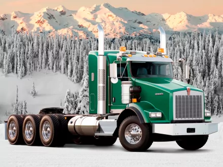HD desktop wallpaper featuring a green Kenworth truck parked in a snowy, mountainous landscape with frosted trees in the background.
