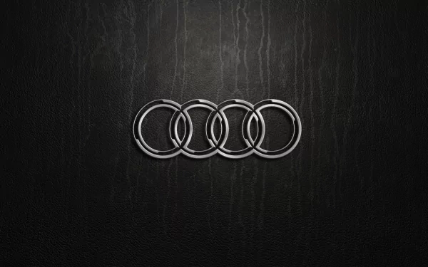A sleek HD wallpaper featuring the Audi logo prominently displayed against a textured black background, showcasing the brand’s iconic four rings.