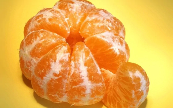 HD PC desktop wallpaper featuring a close-up of a peeled mandarin with vibrant orange segments against a bright yellow background.