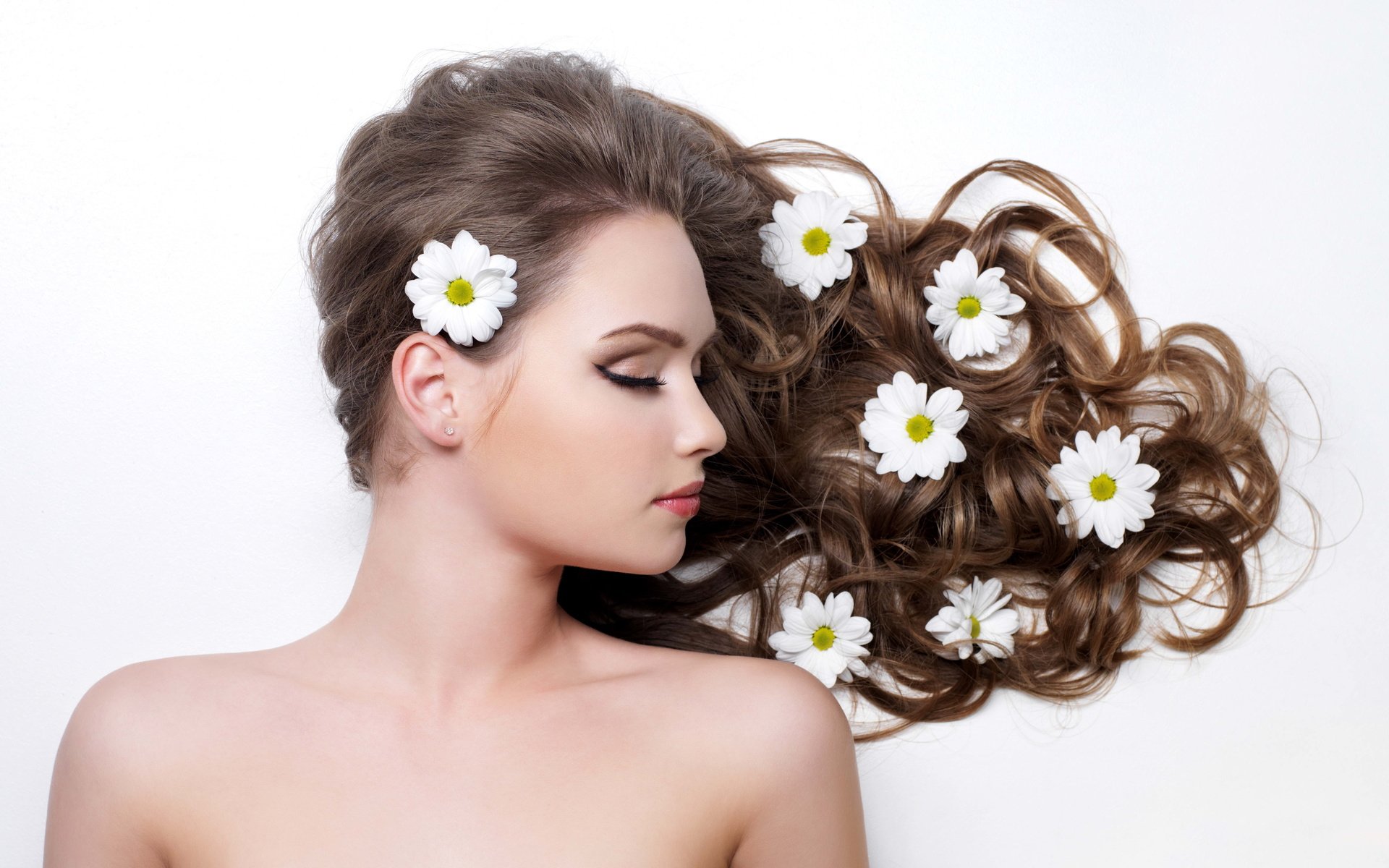 A serene woman with flowing hair adorned with daisies, captured in high definition, creates a beautiful and elegant desktop wallpaper or background.