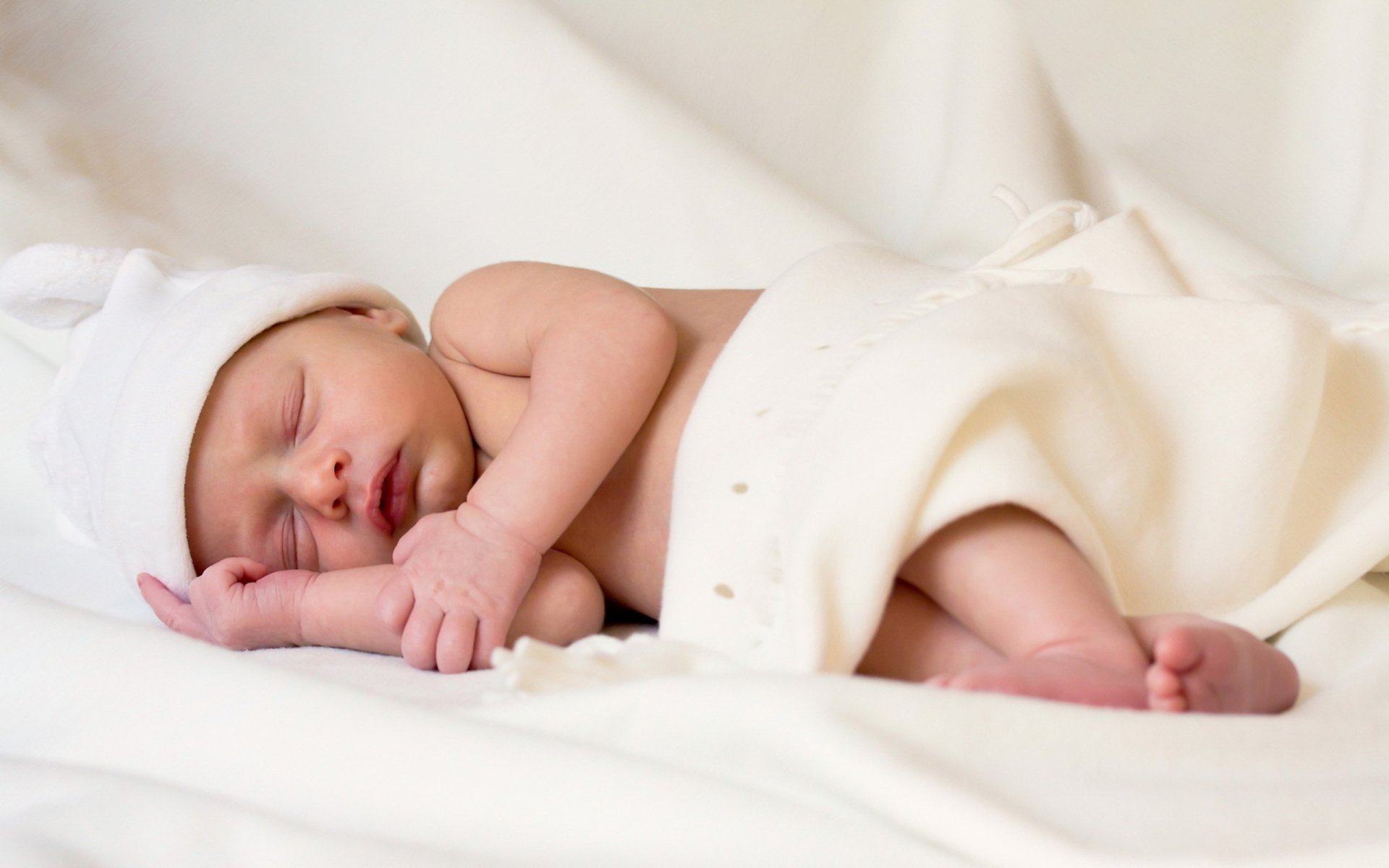 A serene image of a sleeping baby wrapped in a soft blanket, wearing a light hat, creating a peaceful atmosphere. This photography serves as a charming HD desktop wallpaper and background.