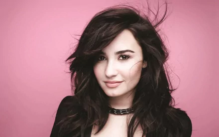 HD PC desktop wallpaper featuring Demi Lovato with tousled dark hair against a pink background, highlighting her music career.