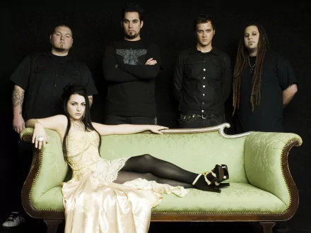 HD desktop wallpaper featuring the rock band Evanescence, with members standing against a dark background and the lead singer lounging on an elegant green sofa.