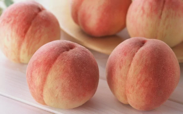 A vibrant HD desktop wallpaper featuring fresh, ripe peaches arranged artfully on a light surface, showcasing their rich colors and smooth textures.