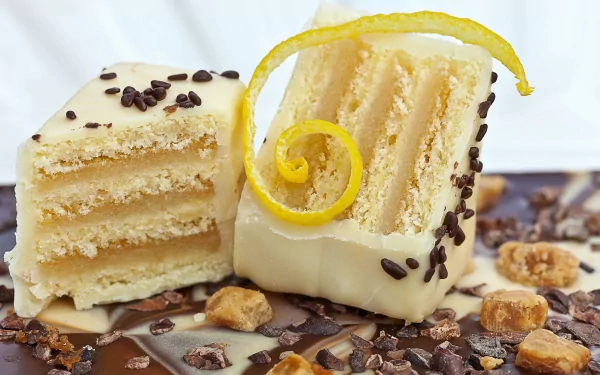 A close-up of a layered cake, featuring a creamy exterior and topped with lemon zest and chocolate sprinkles, presented on a chocolate base. A vibrant 4K Ultra HD wallpaper for food lovers.