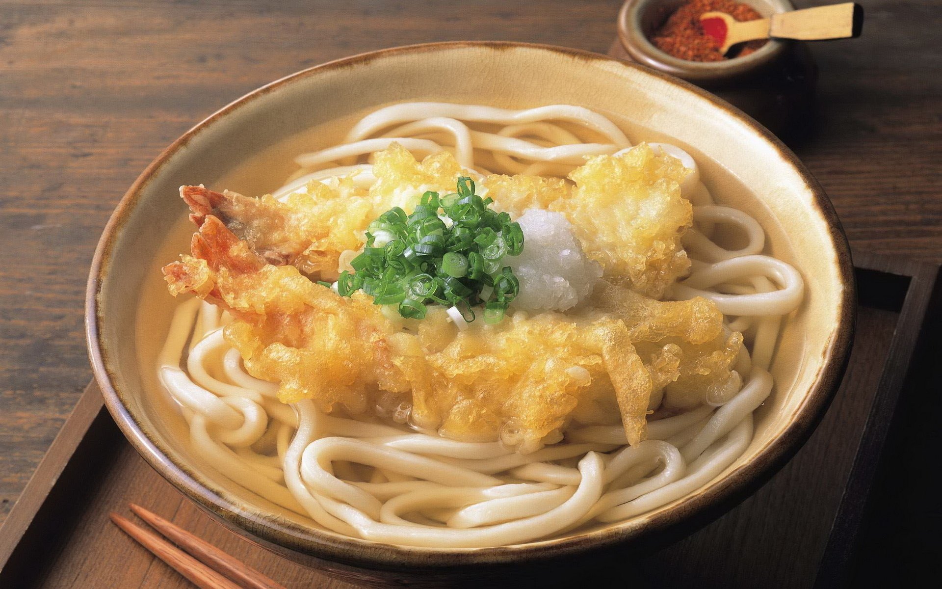 HD PC desktop wallpaper showcasing a bowl of udon pasta topped with tempura shrimp and green onions on a wooden table.