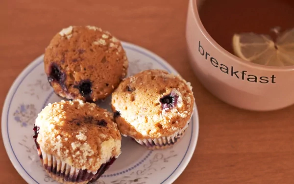 Close-up of three blueberry muffins on a plate next to a cup labeled breakfast, captured in 4K Ultra HD for a vibrant PC desktop wallpaper and background.