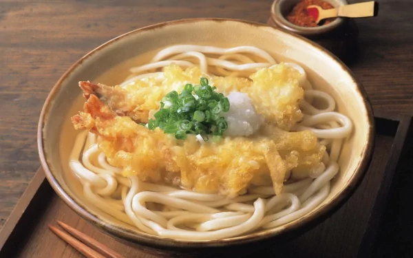 HD PC desktop wallpaper showcasing a bowl of udon pasta topped with tempura shrimp and green onions on a wooden table.