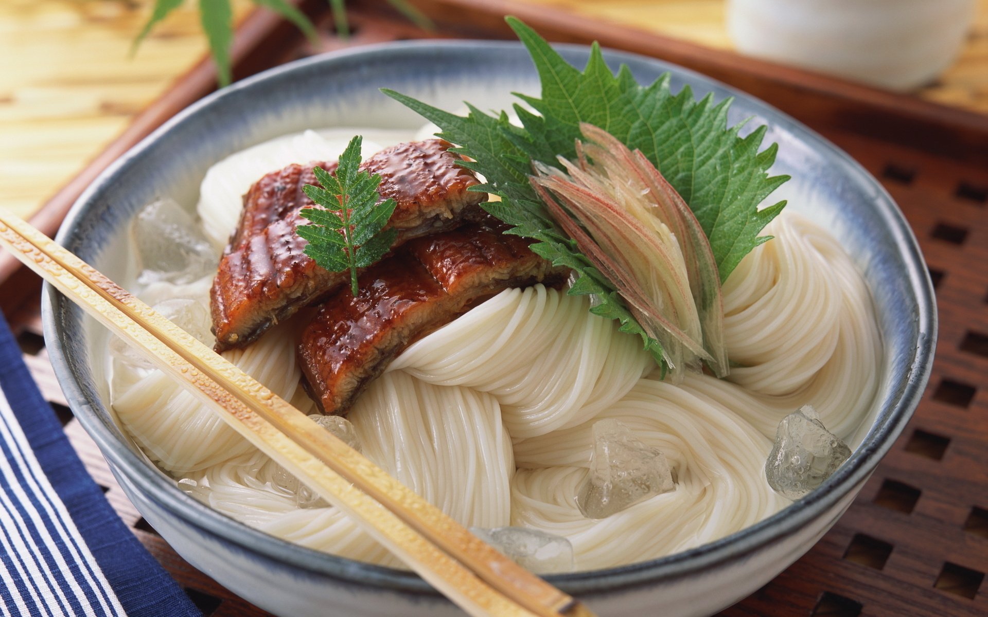 A beautifully presented bowl of fish on a bed of noodles, garnished with fresh herbs, capturing the essence of Japanese cuisine. This HD wallpaper showcases vibrant food art.