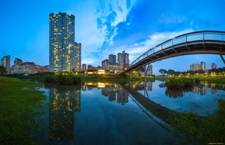 A serene cityscape at dusk, featuring modern skyscrapers and a bridge reflecting in a calm river, showcasing the beauty of urban life in this HD desktop wallpaper.