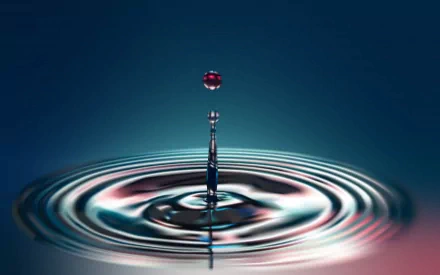 An artistic HD wallpaper featuring a water drop creating ripples on a calm surface, capturing the elegance of fluid motion and vibrant colors.