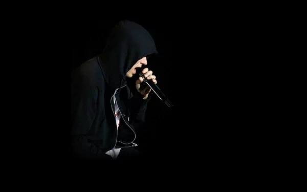 HD desktop wallpaper of Eminem wearing a black hoodie, holding a microphone against a dark background.