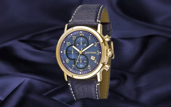 HD desktop wallpaper of a Jack Pierre man-made watch with a blue dial and gold case resting on dark blue fabric.