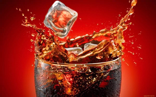 HD PC desktop wallpaper featuring a close-up of a glass filled with a dark fizzy drink and ice cubes splashing against a vibrant red background.