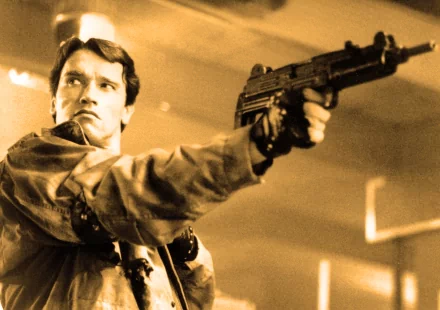 An HD desktop wallpaper featuring an iconic scene from The Terminator, showcasing a determined character aiming a gun in a tense moment.