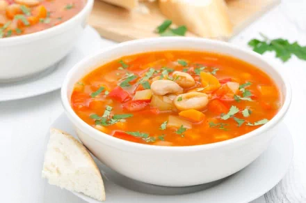 A vibrant bowl of soup with colorful vegetables and herbs, accompanied by a slice of bread. This HD image serves as a warm and inviting desktop wallpaper background.