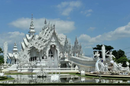 A 4K Ultra HD desktop wallpaper of Wat Rong Khun, a stunning white religious temple with intricate, ornate architecture under a bright blue sky.