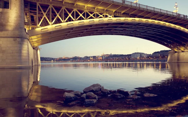 A stunning view of Margaret Bridge in Budapest, Hungary, showcasing its intricate architecture reflected in the calm waters below. An inviting HD wallpaper for any desktop background.