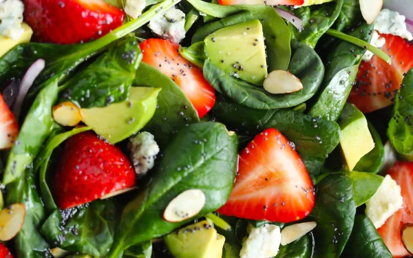A close-up view of a vibrant salad featuring fresh spinach, strawberries, avocado, and almonds. This colorful image serves as an appealing HD desktop wallpaper and background.
