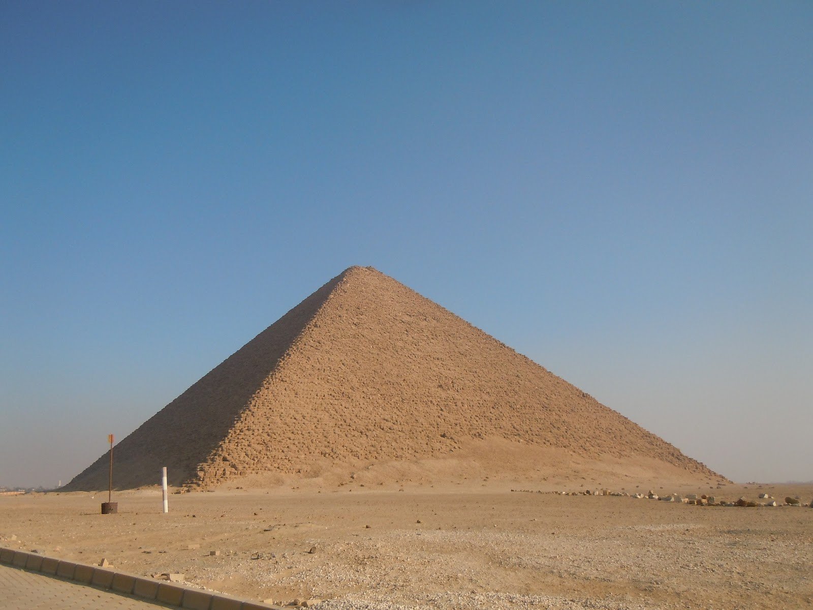 HD PC desktop wallpaper of a man-made pyramid rising from a sunlit desert beneath a clear blue sky.