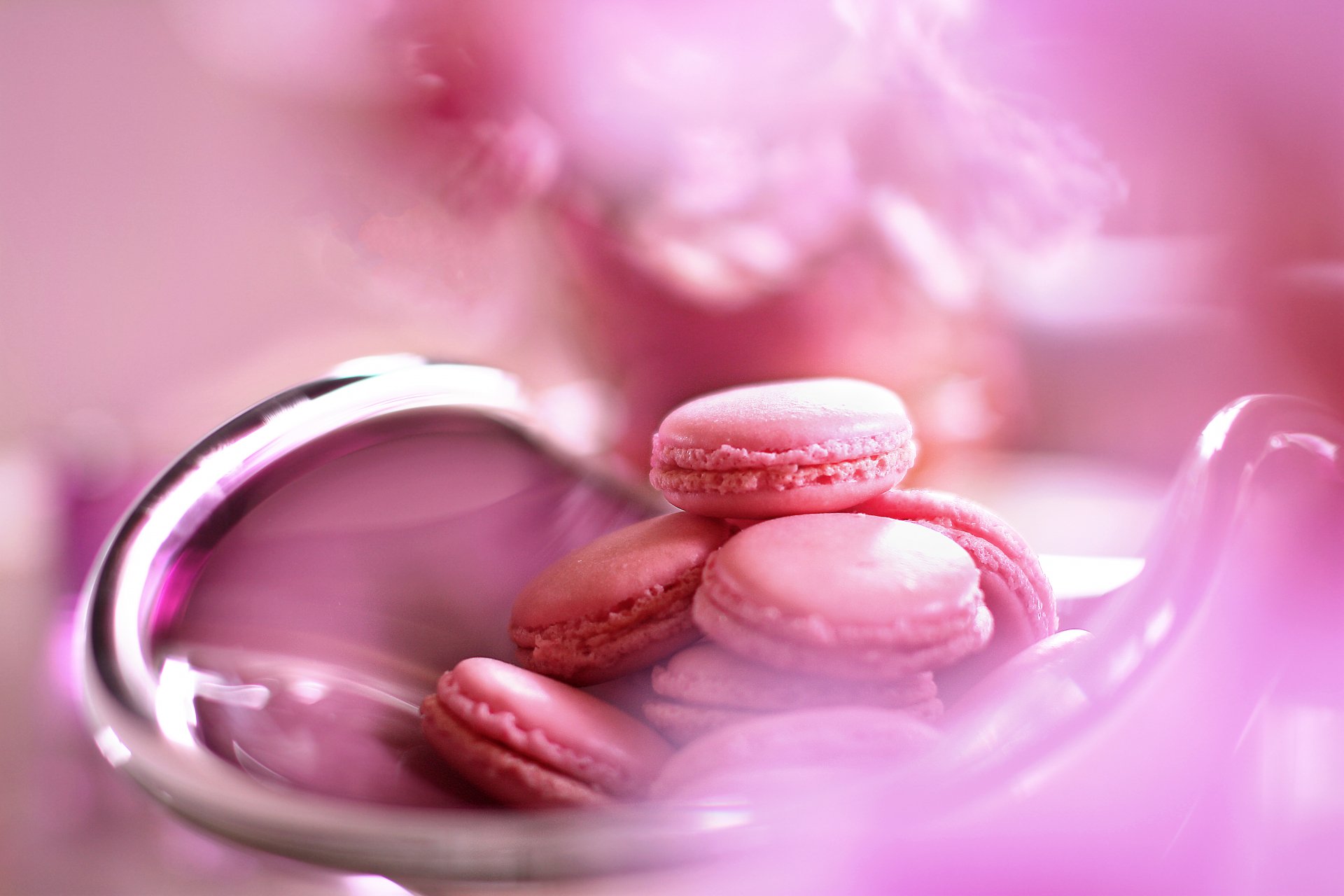 A close-up of delicate pink macarons arranged in a shiny bowl, surrounded by soft pink hues, creating an elegant food-themed 4K Ultra HD desktop wallpaper.