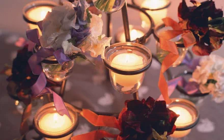 A beautifully arranged display of candles amidst colorful flowers and ribbons, creating a warm and inviting atmosphere. This high-definition photo serves as a stunning desktop wallpaper and background.