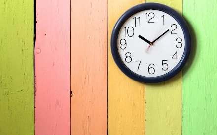 A modern wall clock hangs against a vibrant, multicolored wooden background, creating an engaging visual for an HD PC desktop wallpaper.