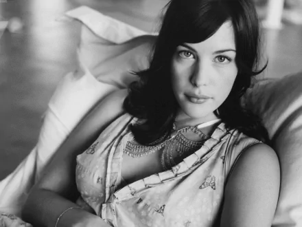 Black and white HD desktop wallpaper featuring a close-up portrait of celebrity Liv Tyler reclining on a couch, showcasing a calm and elegant expression.