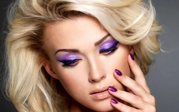 A close-up of a woman’s face showcasing vibrant purple makeup and stylish blonde hair, set against a soft gray background, serves as eye-catching HD wallpaper.