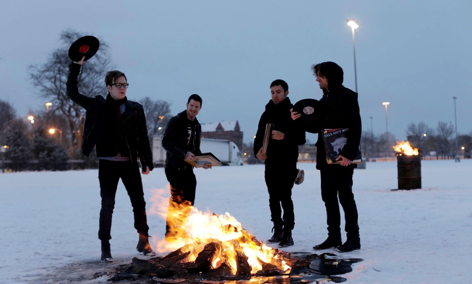 HD PC desktop wallpaper featuring Fall Out Boy band members standing around a bonfire in a snowy outdoor setting, blending music and winter atmosphere.