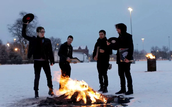 HD PC desktop wallpaper featuring Fall Out Boy band members standing around a bonfire in a snowy outdoor setting, blending music and winter atmosphere.
