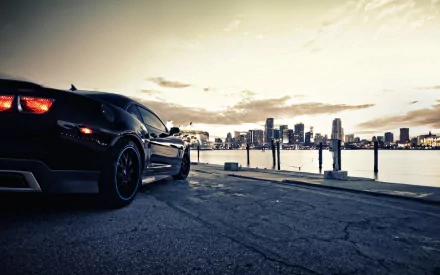 HD desktop wallpaper of a Chevrolet Camaro SS parked near the waterfront with a silhouette of Miami's skyline at sunset in the background.