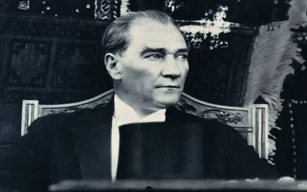 Black and white HD wallpaper photo of a distinguished man in a suit, sitting and looking to his side, showcasing a classic and timeless moment.