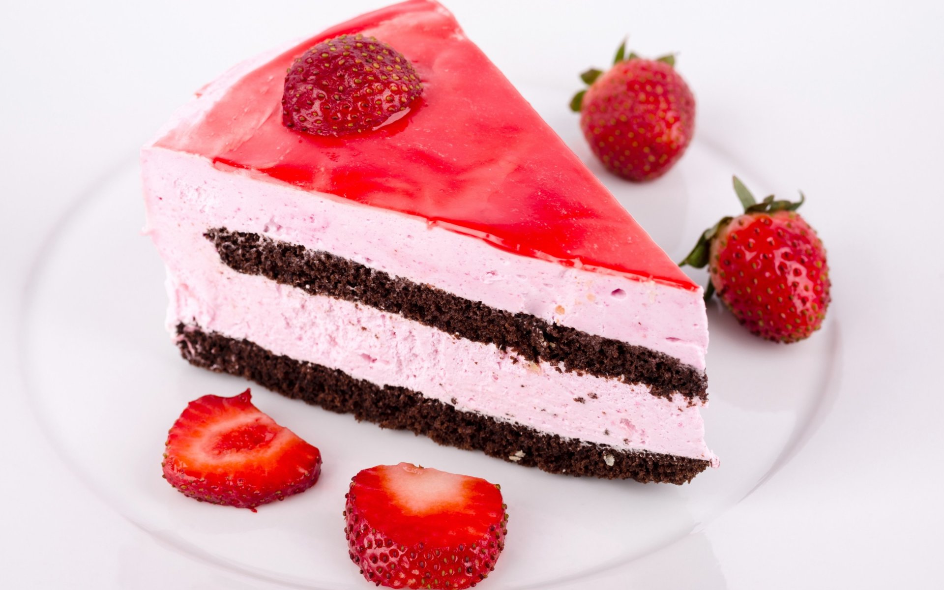 A delicious slice of strawberry cake features creamy layers and a glossy red topping, surrounded by fresh strawberries, serving as a tempting dessert backdrop.