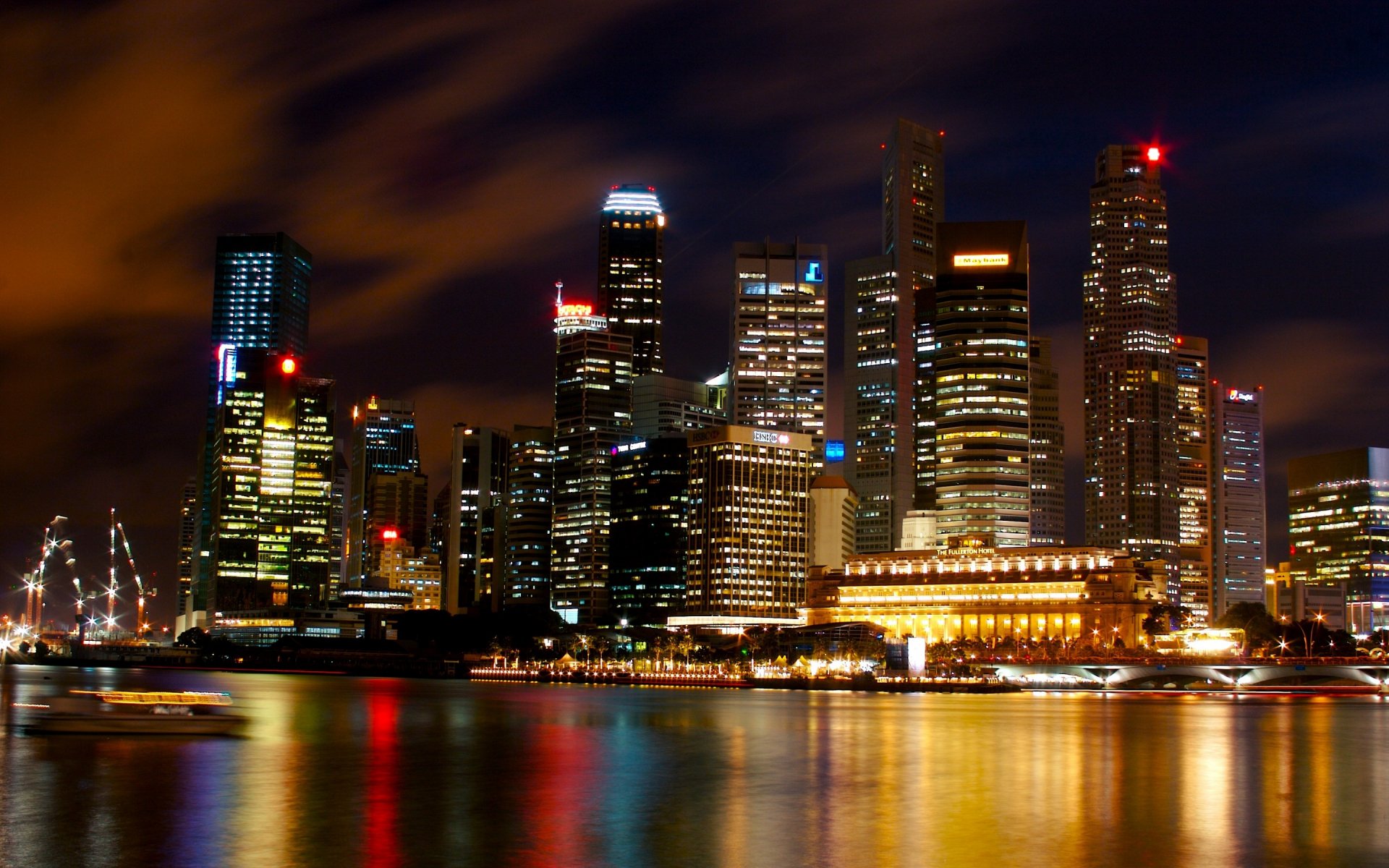 HD desktop wallpaper showcasing a vibrant man-made skyline of Singapore at night with illuminated skyscrapers reflecting on calm water.