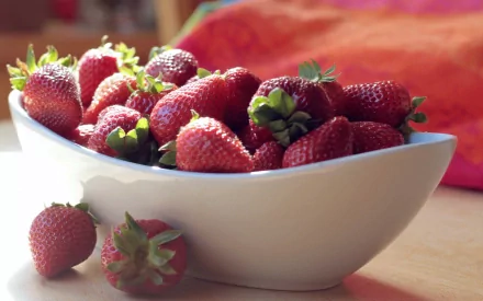 HD PC desktop wallpaper featuring a close-up of fresh strawberries overflowing in a white bowl with a warm, softly blurred background.