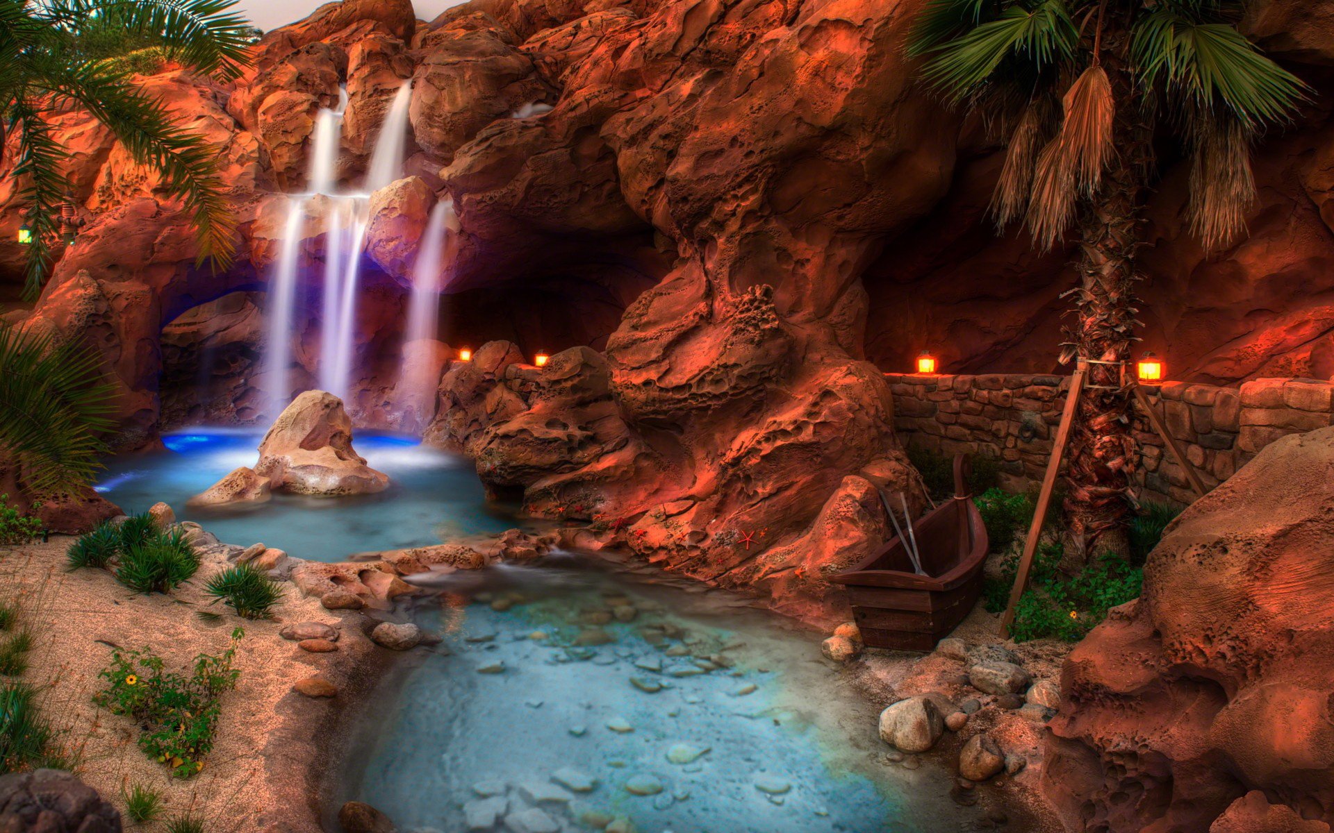 A serene waterfall cascades over vibrant rocks, surrounded by lush greenery and tranquil waters, creating a stunning nature scene in this HD desktop wallpaper.